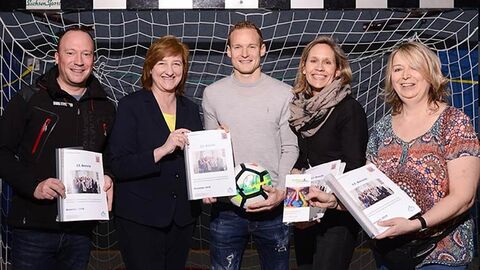 Personen stehen in einem Fußballtor und präsentieren den Tätigkeitsbericht.