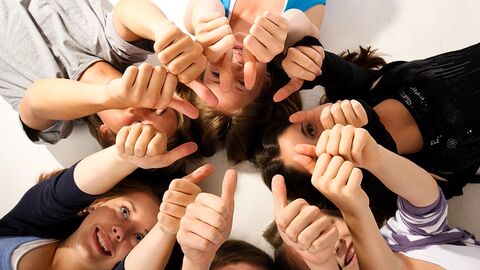 Daumen hoch "Daumen hoch"-Geste von mehreren jungen Menschen, die auf dem Boden liegen, aus der Vogelperspektive aufgenommen.